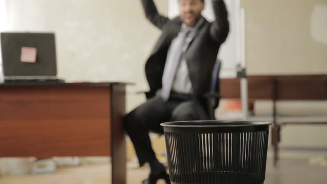 Loafer at office, businessman throws papers in trash can, dreams of vacation