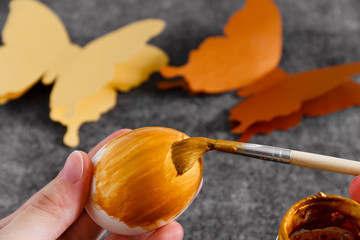 Workspace with easter decoration. Woman paints Easter eggs, slide view. Selective focus