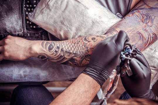 Professional tattooer makes tattoo in tattoo studio