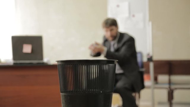 Loafer at office, businessman throws papers in trash can, dreams of vacation