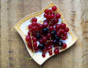 currant berries on a plate on a wooden background