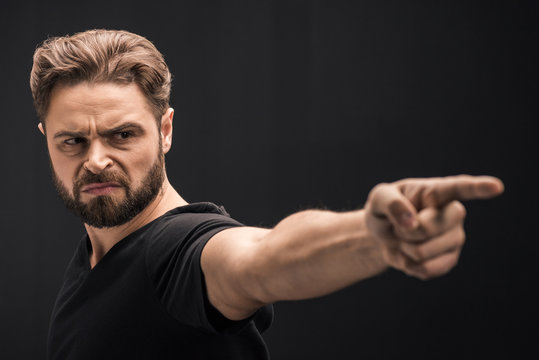 angry bearded man pointing on black with copy space
