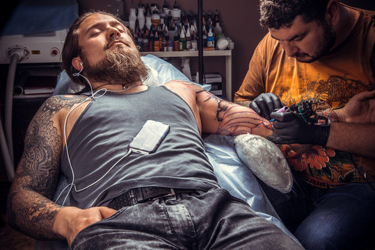 Professional tattooer at work in tattoo parlor