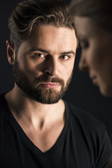 Close-up portrait of young serious man and woman on black