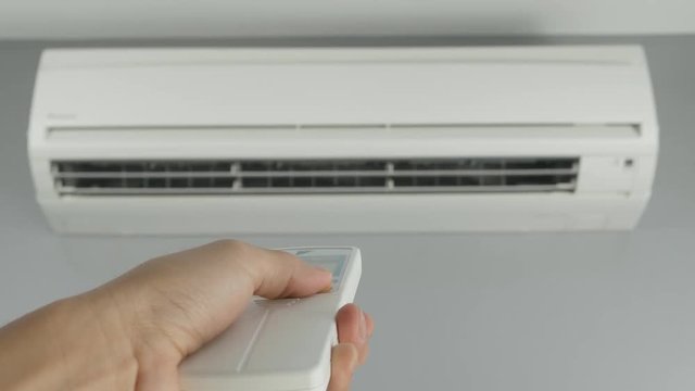 4k of hand holding remote control and turning on air conditioner at home
