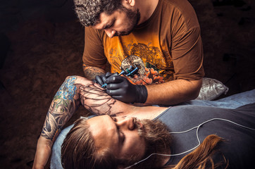 Tattoo master doing tattoo in tattoo studio