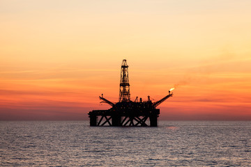 Fototapeta na wymiar Offshore Jack Up Rig in The Middle of The Sea at Sunset Time 