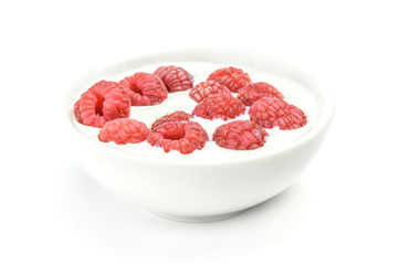 Ripe raspberry into milk in the bowl on white background