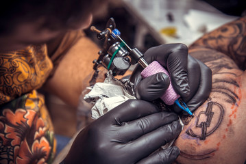Fototapeta na wymiar Professional tattooist doing tattoo in studio