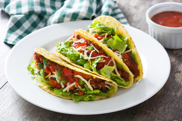Traditional Mexican tacos with meat and vegetables on wooden background
