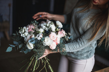 Florist at work: pretty young blond woman holds fashion modern bouquet of different flowersv