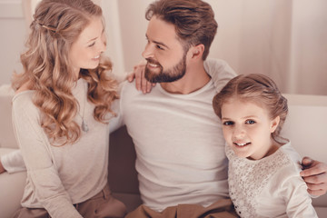 Happy young family with one child sitting embracing together at home