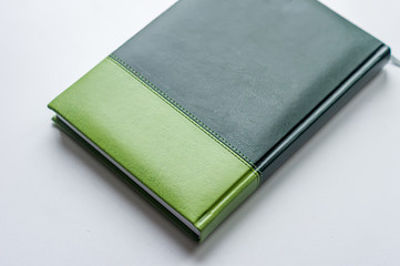 green business note book lying on the white surface