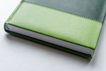 green business note book lying on the white table