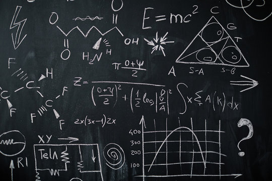 Background shot of blackboard with scientific and algebraic formulas and graphs written on it in chalk