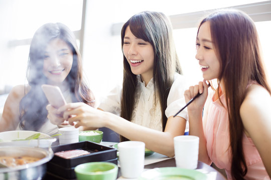 young Women group  Eating hot pot and taking picure by phone