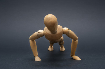 Person represented by a wooden dummy making push ups during his gym training.