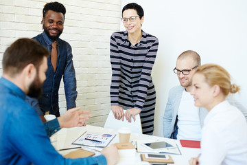 Fototapeta premium Group of creative designers looking at their bearded colleague with interest while he presenting them his ideas concerning joint project in modern boardroom