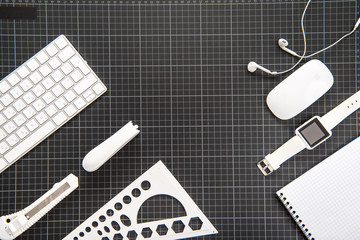 Top view of smartwatch, earphones, computer mouse and office supplies on black