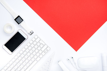 Flat lay of office supplies, keyboard, smartphone, smartwatch and red paper