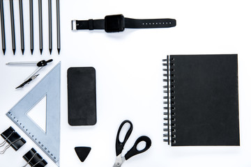 Flat lay of black office supplies, smartphone and smartwatch on white