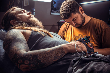 Fototapeta premium Master showing process of making a tattoo in studio