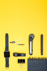 Flat lay of office supplies, smartwatch and notepad with copy space on yellow