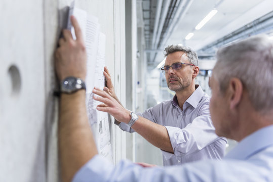 Two businessmen discussing construction plan at concrete wall