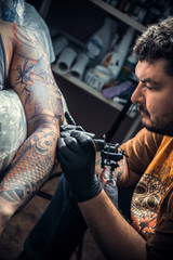 Professional tattooist makes tattoo in studio