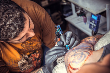 Professional tattoo artist working tattooing in tattoo studio