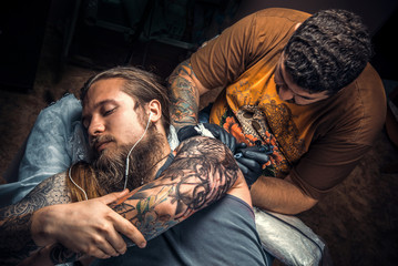 Fototapeta premium Tattoo specialist showing process of making a tattoo in tattoo parlor