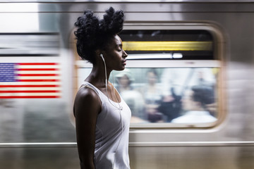 USA, New York City, Manhattan, woman with earphones on subway station platform