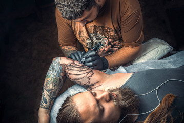 Tattooer at work in tattoo studio