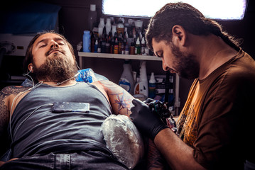 Tattooer makes cool tattoo in tattoo parlor