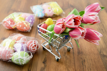 shopping cart with easter items like bunch of tulips and eggs.