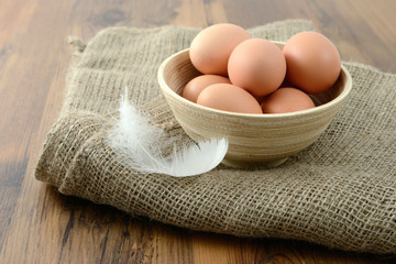 bowl with natural beige eggs on wooden table background