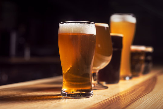 Several different beers are standing in a row at the bar
