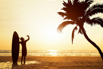 Happy friends standing drinking with surfboards on the beach