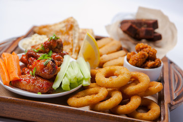 Smoked snacks for beer on wooden board, flat lay. Top view on assortment of unhealthy smoked dining.