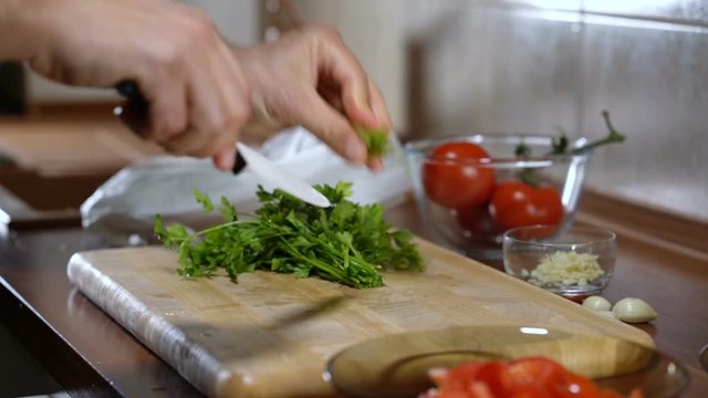 man cuts parsley for cooking bruschetta