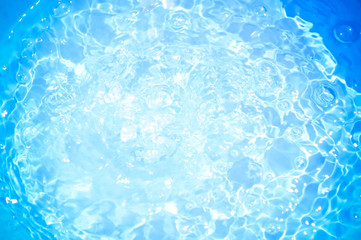 Blue pool water with sun reflections.Shining blue water ripple background.