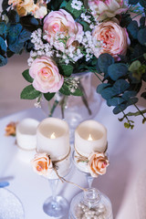 Decorated candles and glasses vase with bouquet of roses. Romance and love concept. Close-up