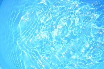 Blue pool water with sun reflections.Shining blue water ripple background.