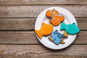 Plate with tasty fish cookies on wooden table.