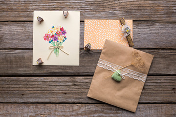 Envelope with white ribbon and two postcards with flowers.