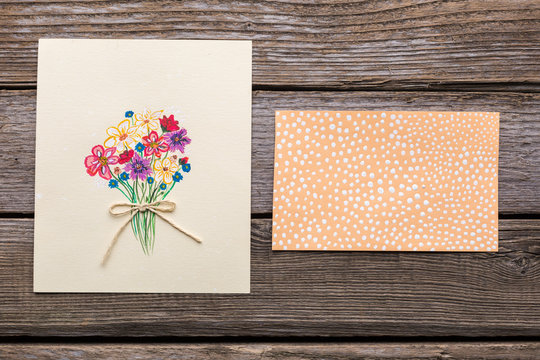 Greeting card with flowers on wooden background.
