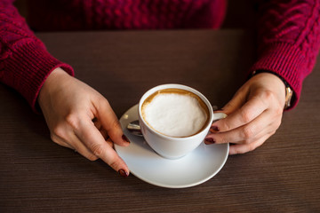 Crop female holding cup of latte
