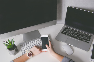 hands holding smartphone and with different devices on table, mock up