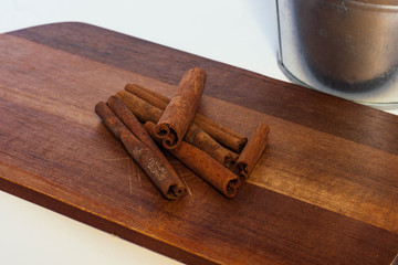 Cinnamon sticks on wooden board on white background
