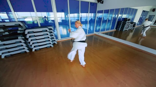 Young woman in white kimono practice the karate in the gym